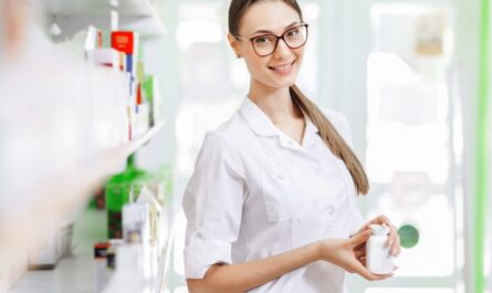 Pharmacienne portant une blouse blanche dans l’espace de vente d’une officine.